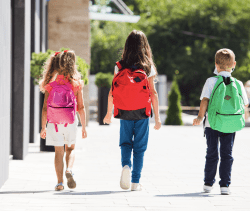 Elementary Students walking into school with back to school essentials and new backpacks