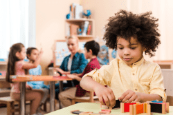 Photo of Montessori Student in classroom learning with hands on technique emphesized in Montesssori teaching and practiced at Montessori House in Richmond, Texas.