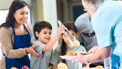 Family volunteering and working together to feed others in need. Montessori Children and Family.