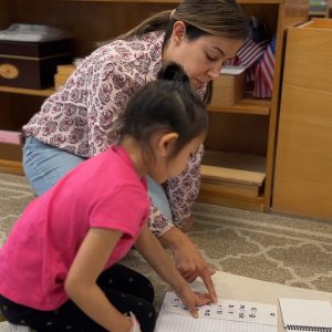 Early Childhood Montessori Classroom with Teacher/Guide instructing a young femal student in the Literacy Program.